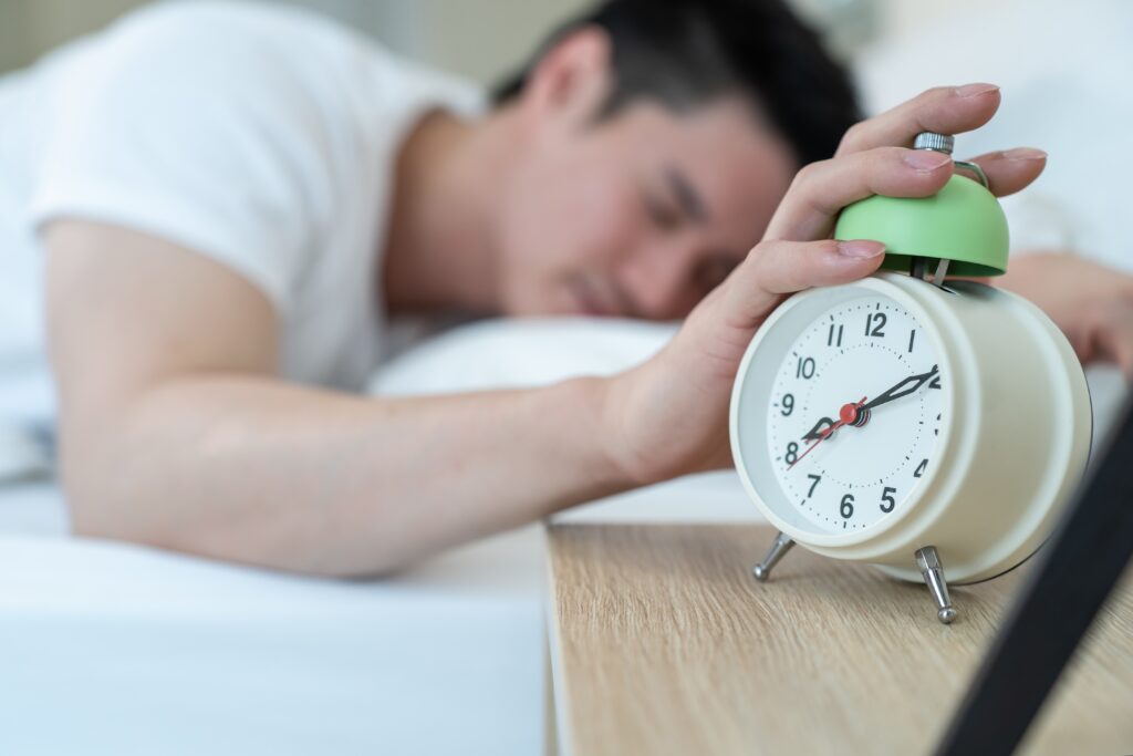 man turn off alarm clock ringing in the morning