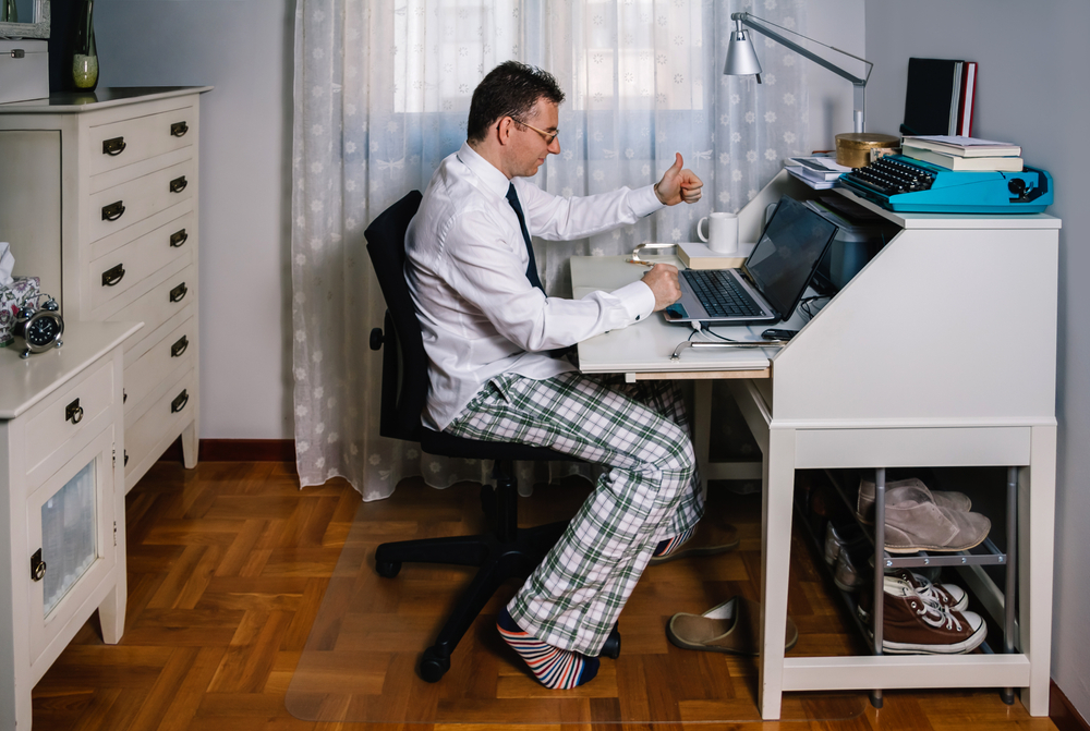 Man working from home with laptop wearing shirt, tie and pajama pants